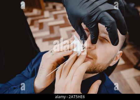 Maître barber enlève les cheveux du nez de l'homme avec la cire, la procédure de beauté d'épilation Banque D'Images