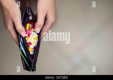 jeune femme ouvre un portefeuille et voit dans lui un grand nombre de comprimés de différentes couleurs Banque D'Images