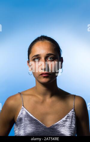 Studio portrait de la jeune femme indienne sur fond bleu ciel. Gros plan moyen. Regarder l'appareil photo. Banque D'Images