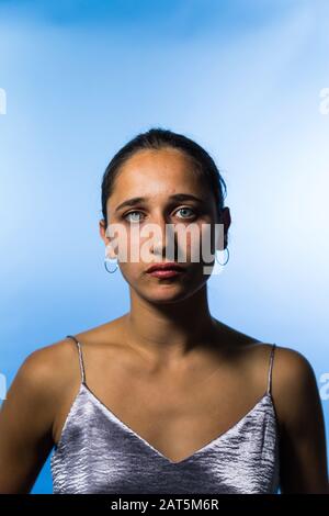 Studio portrait de la jeune femme indienne sur fond bleu ciel. Gros plan moyen. Regarder l'appareil photo. Banque D'Images