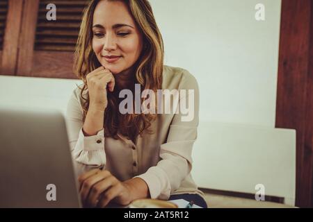 Jeune femme travaillant sur son ordinateur portable tout en étant assise au café. Femme d'affaires travaillant sur un ordinateur portable à partir d'un café. Banque D'Images