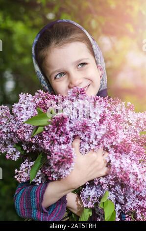 Une petite fille avec un bouquet de lilas dans ses mains Banque D'Images