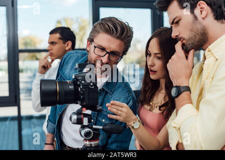 mise au point sélective d'un directeur artistique regardant l'appareil photo numérique près des assistants Banque D'Images