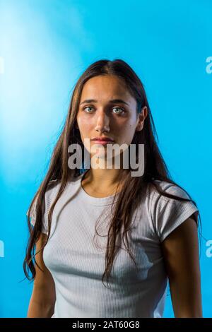 Portrait de la jeune femme du Moyen-Orient sur fond de studio bleu. Prise de vue moyenne. Regarder l'appareil photo. Banque D'Images