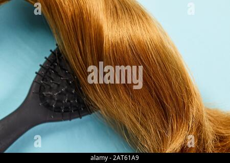 Vue de dessus des cheveux bruns brillants et de la brosse à cheveux sur fond bleu Banque D'Images