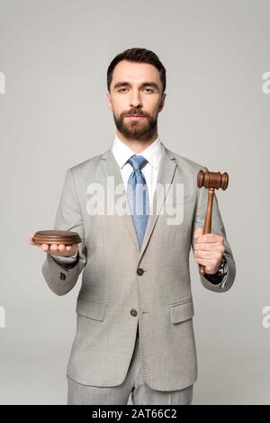 juge confiant tenant le gavel tout en regardant la caméra isolée sur gris Banque D'Images