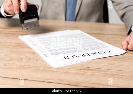 vue partielle de l'homme d'affaires tenant le timbre près du contrat isolé sur gris Banque D'Images