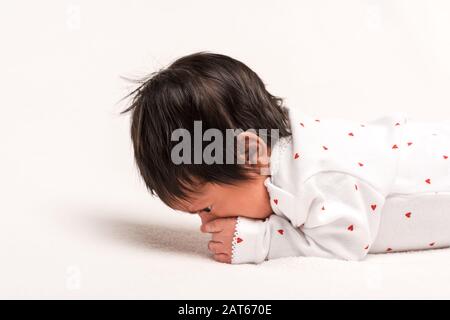 race mixte nouveau-né dans la barboteuse de bébé posée sur blanc Banque D'Images