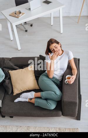 vue sur le dessus de la fille fatiguée refroidissement du canapé avec tasse de thé Banque D'Images