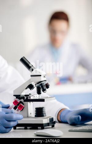 vue rognée du consultant en génétique qui tient des tubes à essai en laboratoire Banque D'Images