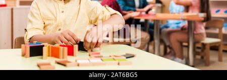 Photo panoramique d'un enfant jouant à un jeu éducatif avec des enfants en arrière-plan à l'école de montessori, vue sur le court Banque D'Images