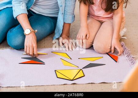 Vue réduite sur les enfants et les enseignants jouant au jeu éducatif sur le sol en classe montessori Banque D'Images