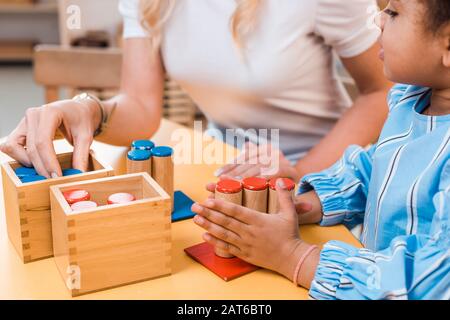 Foyer sélectif des enfants et des enseignants jouant au jeu éducatif au bureau à l'école de montessori Banque D'Images