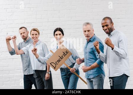 groupe de gens multiculturels se tenant près de la femme tenant un placarde avec le lettrage de demokratie Banque D'Images