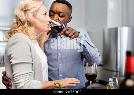 foyer sélectif de l'homme africain américain donnant du verre de vin à un ami dans la cuisine Banque D'Images