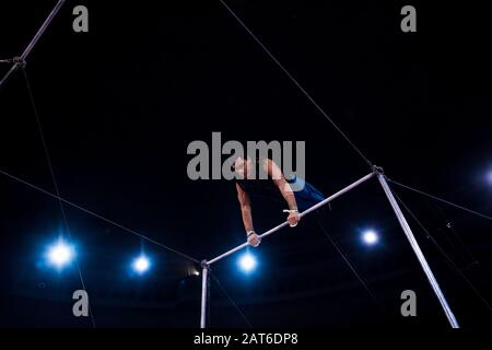 vue en bas angle de beau acrobat en performance sur des barres horizontales dans le cirque Banque D'Images