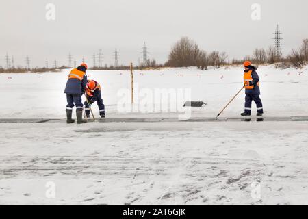 Les employés radeau des blocs de glace le long d'une chaîne coupée un lac gelé Banque D'Images