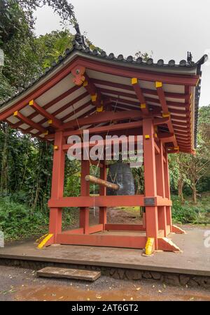 Kaneohe, Oahu, Hawaï, États-Unis. - 11 janvier 2020: Pavillon rouge pour la cloche sacrée géante dans le jardin du temple bouddhiste de Byodo-In. Fond de feuillage plus vert. Banque D'Images