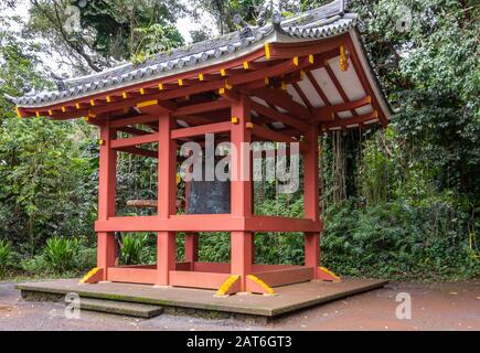 Kaneohe, Oahu, Hawaï, États-Unis. - 11 janvier 2020: Pavillon rouge pour la cloche sacrée géante dans le jardin du temple bouddhiste de Byodo-In. Fond de feuillage plus vert. Banque D'Images