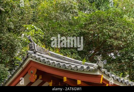 Kaneohe, Oahu, Hawaï, États-Unis. - 11 janvier 2020: Décorations de toit gris au-dessus des poutres rouges du temple bouddhiste Byodo-In. Fond de feuillage plus vert. Banque D'Images