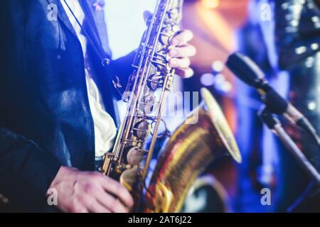 Vue de concert d'un saxophone avec chanteur et groupe musical de jazz en arrière-plan Banque D'Images