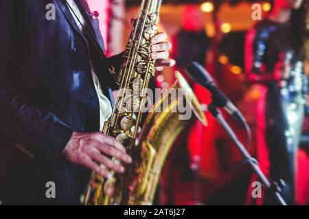 Vue de concert d'un saxophone avec chanteur et groupe musical de jazz en arrière-plan Banque D'Images