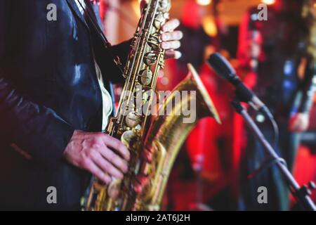 Vue de concert d'un saxophone avec chanteur et groupe musical de jazz en arrière-plan Banque D'Images