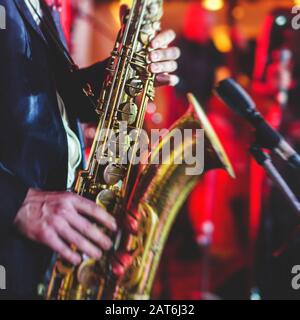 Vue de concert d'un saxophone avec chanteur et groupe musical de jazz en arrière-plan Banque D'Images