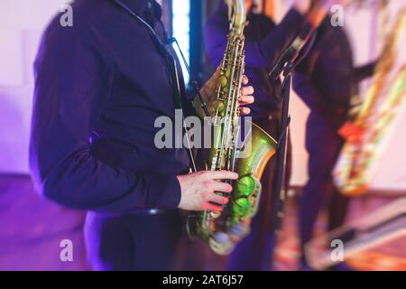 Vue de concert d'un saxophone avec chanteur et groupe musical de jazz en arrière-plan Banque D'Images