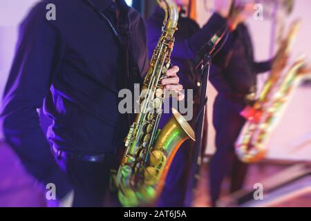 Vue de concert d'un saxophone avec chanteur et groupe musical de jazz en arrière-plan Banque D'Images