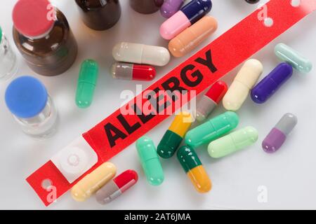 Bracelet d'alerte aux allergies hospitalières avec capsules multicolores et flacons de médicaments. Banque D'Images