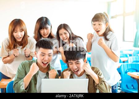 heureux étudiants regardant l'ordinateur portable dans la salle de classe Banque D'Images