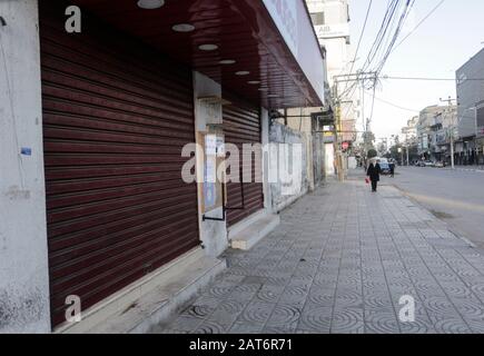 Gaza, Palestine. 30 janvier 2020. Une femme palestinienne passe devant des magasins fermés pendant la grève générale pour protester contre le plan de paix américain dans la ville de Gaza. Crédit: Sopa Images Limited/Alay Live News Banque D'Images