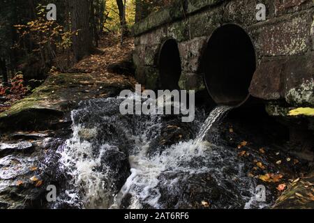 L'eau s'écoule à travers les ponceaux sous un pont en pierre recouvert de lichen. Pris À L'Automne 2018 Dans La Région Naturelle De Houghton Falls State, Bayfield Co., Wisconsin. Banque D'Images