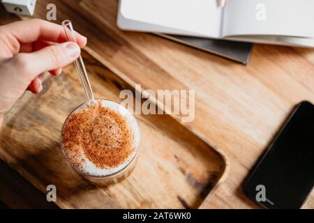 Une tasse de Latte est servie avec un tube en verre sur un bureau en bois. Concept de pause-café. Banque D'Images