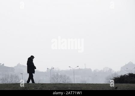 Belgrade, Serbie - 26 janvier 2020: Silhouette d'homme âgé marchant seul sur Ada, sur un jour d'hivers pollués et brumeux Banque D'Images