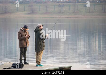 Belgrade, Serbie - 26 janvier 2020: Les gens se tenant sur un quai de fer et pêcher dans le lac Ada en hiver Banque D'Images