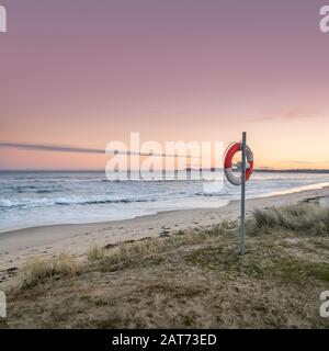 Bouée de sauvetage sur une plage de sable au crépuscule après le coucher du soleil, Ravlunda, Osterlen, Suède, Scandinavie Banque D'Images