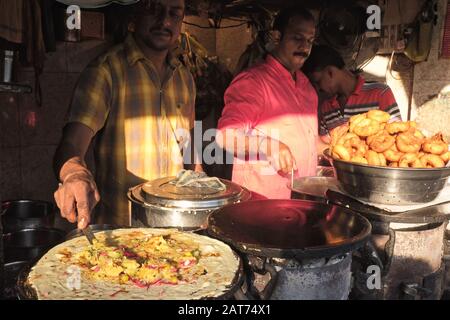 Dans une aire de restauration de Mumbai, en Inde, un cuisinier prépare Masala Dosa, un plat indien populaire. À droite: Un bol de Vade / Vadas, un autre snack populaire Banque D'Images