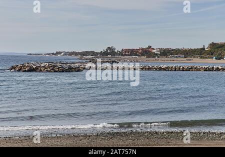 Plage avec brise-lames à Marbella, journée d'été avec sable et vagues Banque D'Images