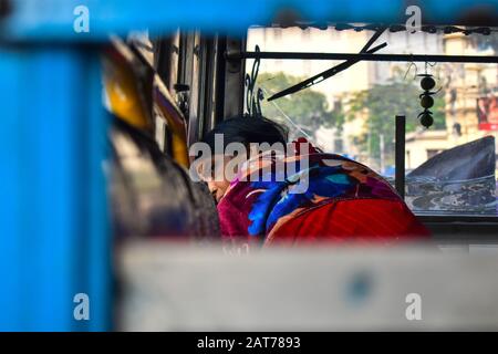 Une femme regarde par la fenêtre de bus à Kolkata, en Inde. Banque D'Images