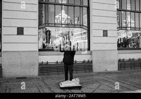 Prague, République tchèque - 01 janvier 2020: Un violoniste sans domicile joue sur le trottoir devant un restaurant Banque D'Images