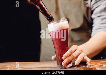 Le cours de l'art de la bière rose cerise de la bouteille en verre, fond sombre Banque D'Images