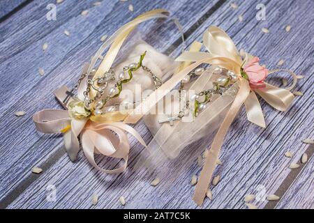 Faveurs de mariage. Boîtes avec ruban rose et or contenant des confettis et un petit cadeau de rosaire chrétien. Banque D'Images