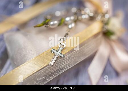 Faveurs de mariage. Boîtes avec ruban rose et or contenant des confettis et un petit cadeau de rosaire chrétien. Banque D'Images