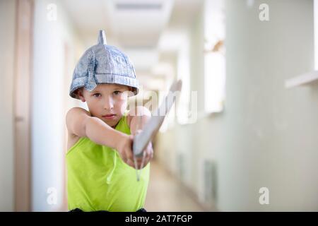 Un enfant joue au guerrier. Drôle de garçon dans un casque avec une épée. Banque D'Images