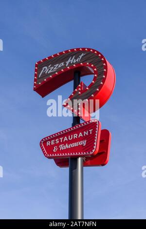 Panneau rouge pour Pizza Hut contre un ciel bleu; restaurant et à emporter, Sixfields, Northampton, Royaume-Uni Banque D'Images