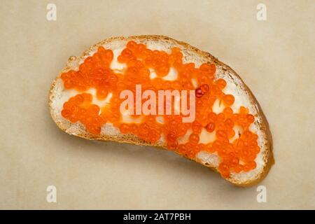 Sandwich au beurre et au caviar de saumon rouge sur du papier kraft brun. Concept de fruits de mer délicats Banque D'Images