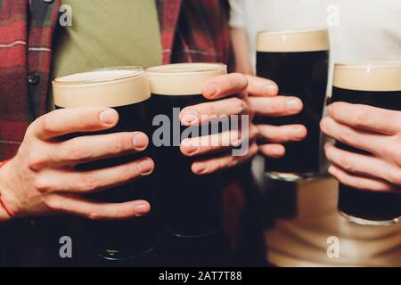 Lunettes de clinking de groupe mâle de bière sombre et claire sur fond de mur de briques Banque D'Images