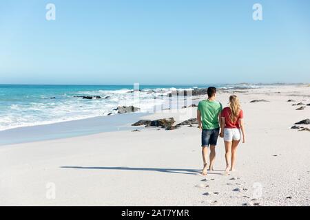 Vue arrière jeune couple marchant à la plage Banque D'Images